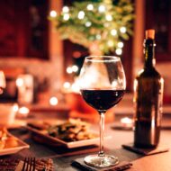 Mesa decorada de navidad con una cena muy rica, copas de vino y una botella de vino en segundo plato. Imagen destacada para un artículo sobre restaurantes nuevo en Madrid recomendados para las cenas de Navidad en 2025