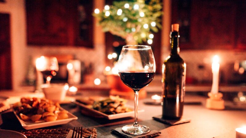 Mesa decorada de navidad con una cena muy rica, copas de vino y una botella de vino en segundo plato. Imagen destacada para un artículo sobre restaurantes nuevo en Madrid recomendados para las cenas de Navidad en 2025