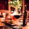 Mesa decorada de navidad con una cena muy rica, copas de vino y una botella de vino en segundo plato. Imagen destacada para un artículo sobre restaurantes nuevo en Madrid recomendados para las cenas de Navidad en 2025
