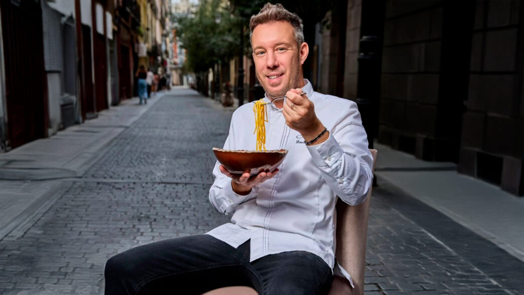 El chef italiano Davide Bonato comiéndose un plato de pasta en mitad de una calle del barrio de Malasaña de Madrid.