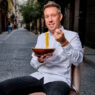 El chef italiano Davide Bonato comiéndose un plato de pasta en mitad de una calle del barrio de Malasaña de Madrid.