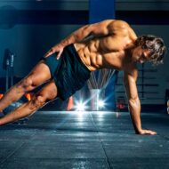 chico joven, de unos 20 años haciendo una plancha lateral en un gimnasio.