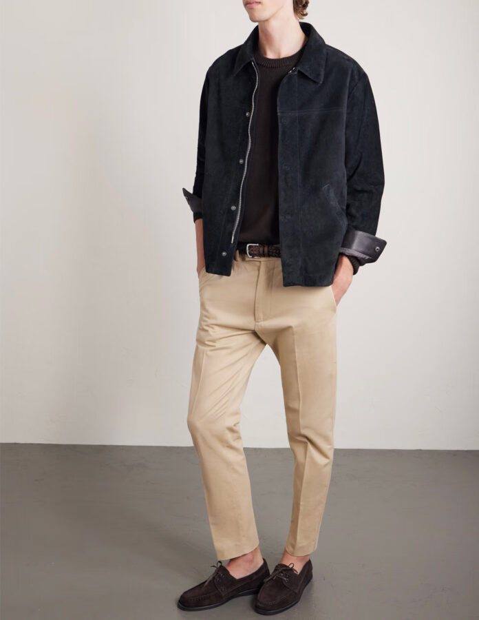 chico joven vestidos con un pantalón beige combinado con un polo azul marino y una chaqueta de ante azul oscura