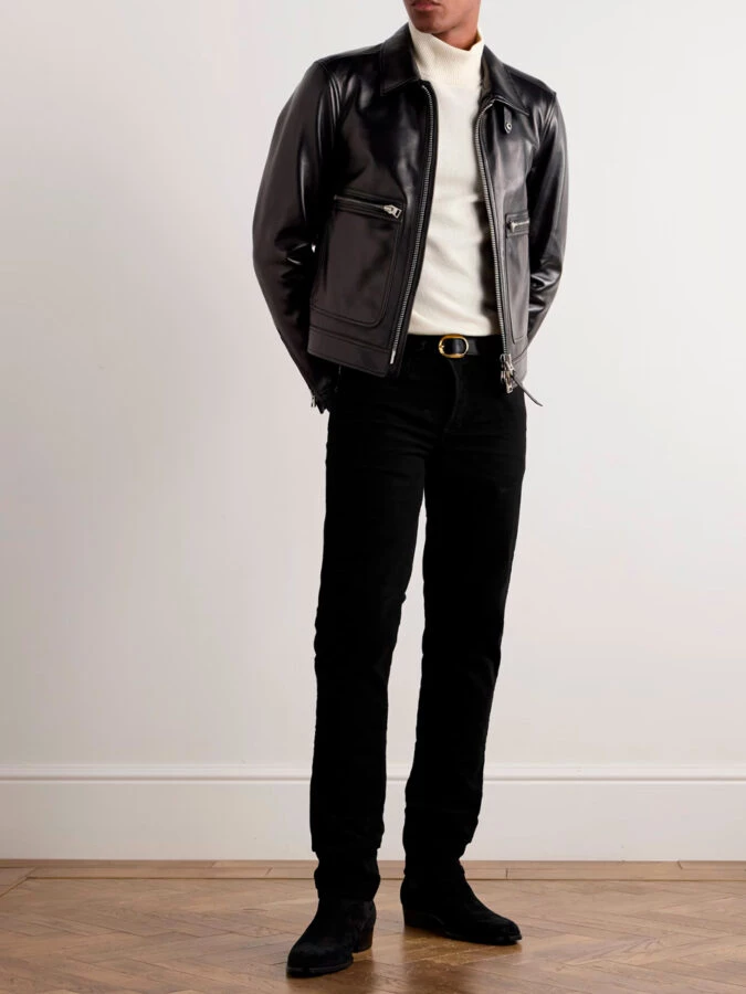 hombre vestido con un pantalón negro, jersey de cuello alto blanco y chaqueta de cuero negra