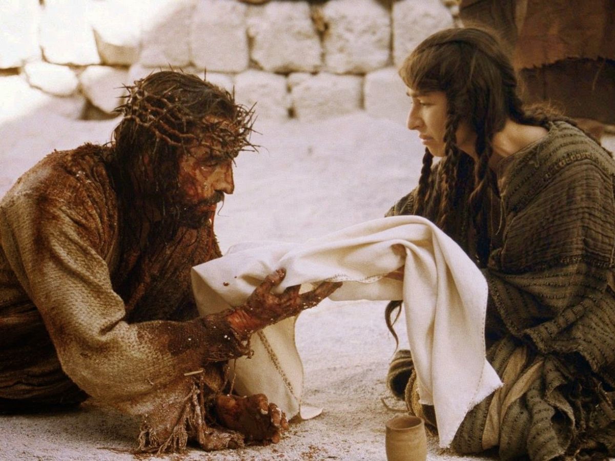 Escena de la película la Pasión en la que Cristo cae al suelo y Verónica le ofrece un paño para limpiarse la cara