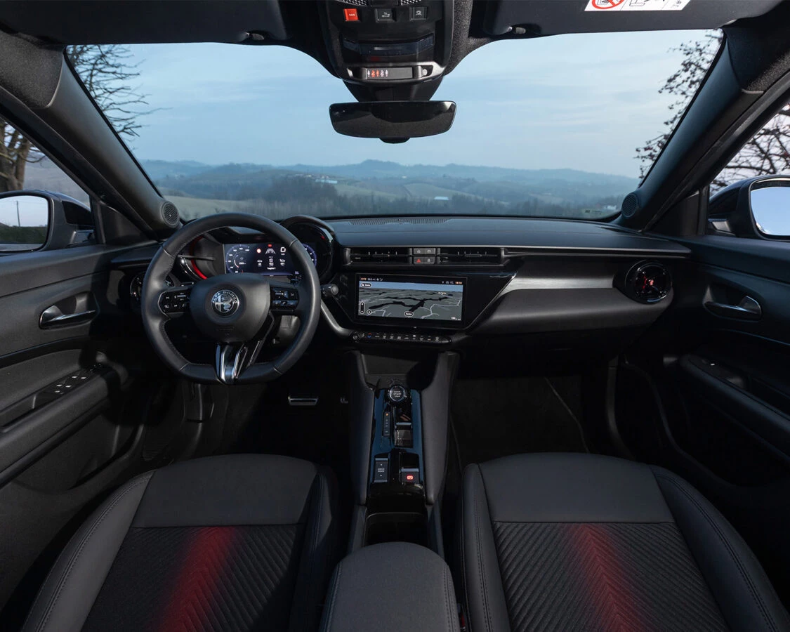 Interior del Alfa Romeo Junior Ibrida Q4 con pantalla central y volante deportivo.