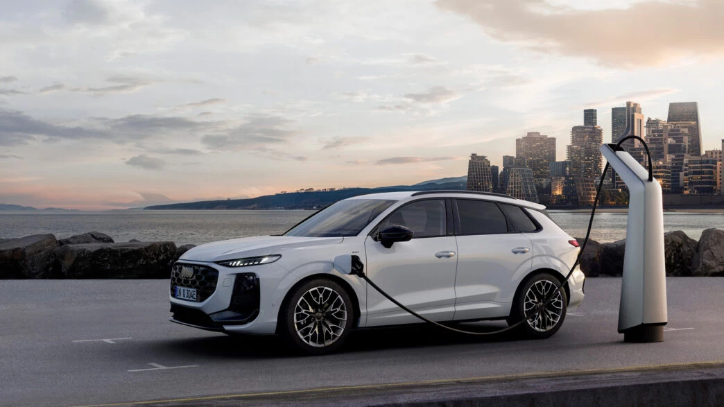 Audi Q3 e-hybrid 2025 cargando en un punto eléctrico frente al mar al atardecer