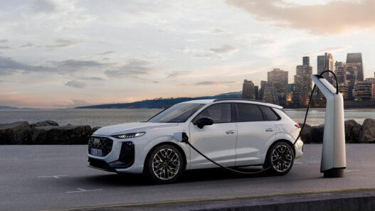 Audi Q3 e-hybrid 2025 cargando en un punto eléctrico frente al mar al atardecer