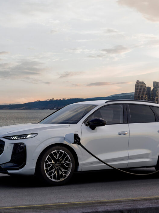 Audi Q3 e-hybrid 2025 cargando en un punto eléctrico frente al mar al atardecer