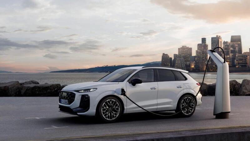 Audi Q3 e-hybrid 2025 cargando en un punto eléctrico frente al mar al atardecer