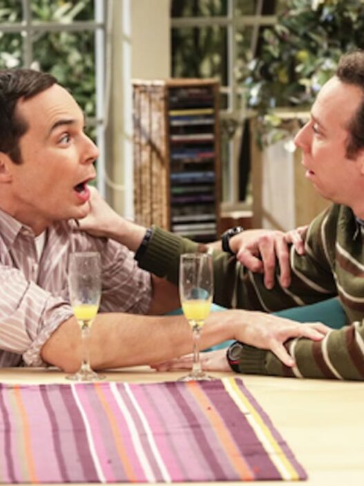 Stuart y Sheldon Cooper conversando en el salón, escena divertida de The Big Bang Theory.