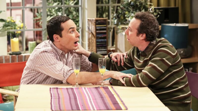 Stuart y Sheldon Cooper conversando en el salón, escena divertida de The Big Bang Theory.