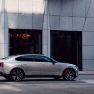 Volvo ES90 2025 en color plateado circulando por una calle urbana con edificios modernos