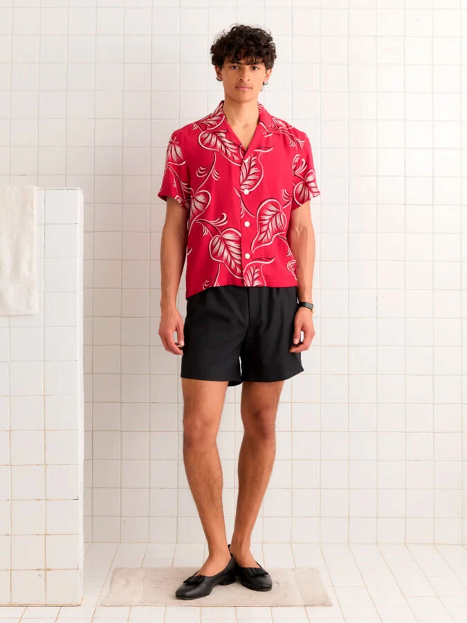 Hombre con camisa de flores roja de Bode y pantalón corto negro, verano 2025