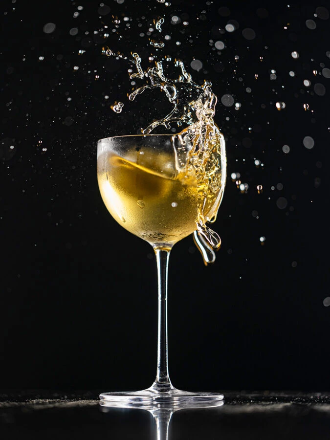  Cóctel dorado de Handshake Speakeasy con efecto splash sobre fondo oscuro