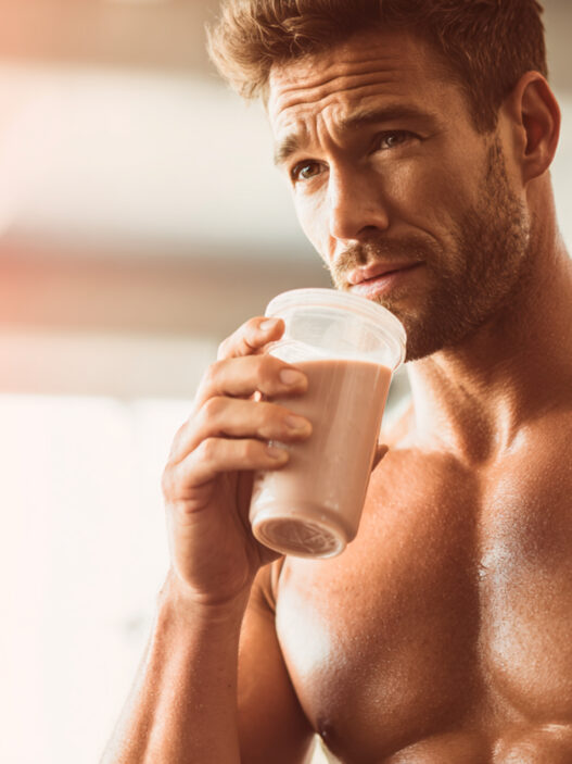 hombre de 40 años muy fuerte tomándose un batido de proteínas en un gimnasio