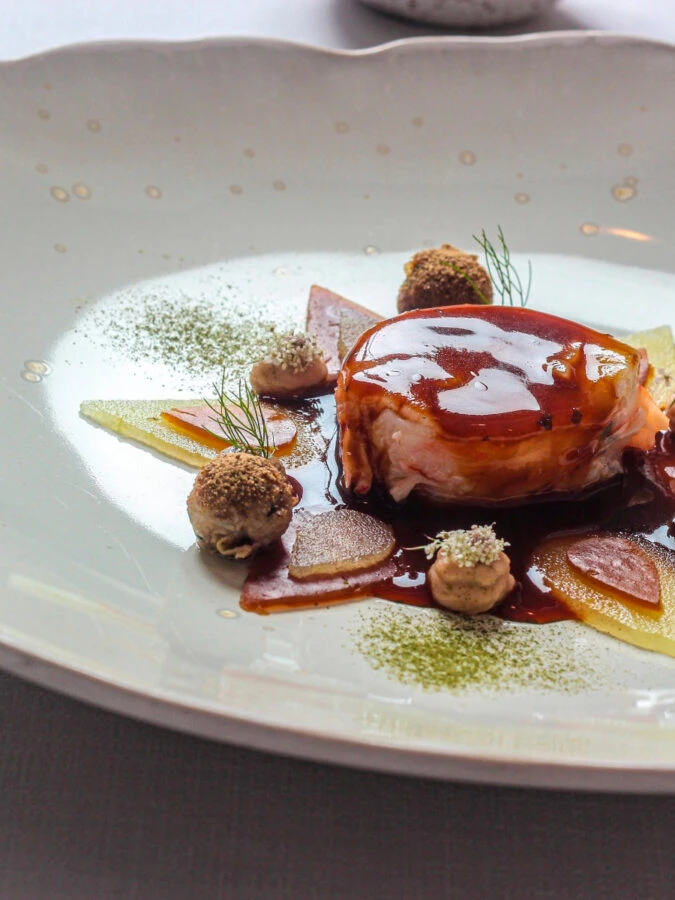 Plato principal del menú degustación del restaurante Andreu Genestra en Mallorca con salsa y guarniciones vegetales