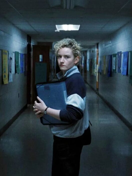 Secuencia de la película Weapons en la que se ve a Julia Garner (Justine) mirando hacia atrás en un pasillo del colegio