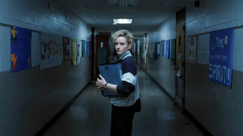 Secuencia de la película Weapons en la que se ve a Julia Garner (Justine) mirando hacia atrás en un pasillo del colegio