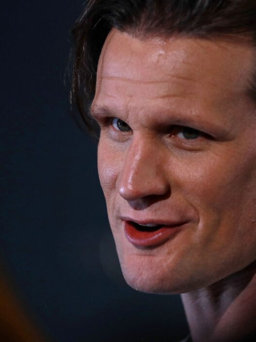 Primer plano de Matt Smith en un evento con fondo oscuro.