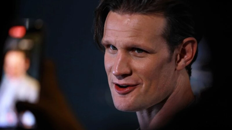 Primer plano de Matt Smith en un evento con fondo oscuro.