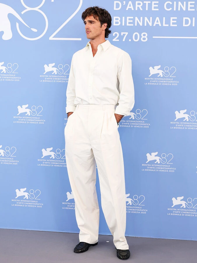 Jacob Elordi con conjunto blanco de Bottega Veneta en el photocall azul del Festival de Cine de Venecia 2025.