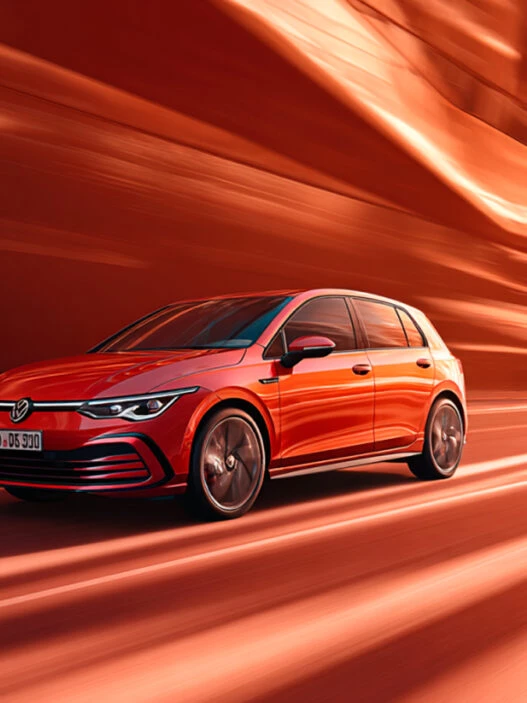 coche Golf eHybrid 2025 de color rojo circulando en una ciudad de esilo futurista. Imagen para ilustrar un artículo sobre los coches que menos consumen de 2025