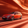 coche Golf eHybrid 2025 de color rojo circulando en una ciudad de esilo futurista. Imagen para ilustrar un artículo sobre los coches que menos consumen de 2025