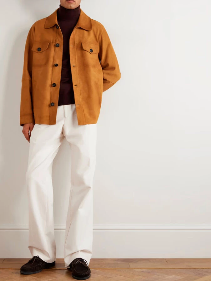 Chaqueta de ante color caramelo combinada con jersey burdeos de cuello alto, pantalones blancos acampanados y náuticos marrones