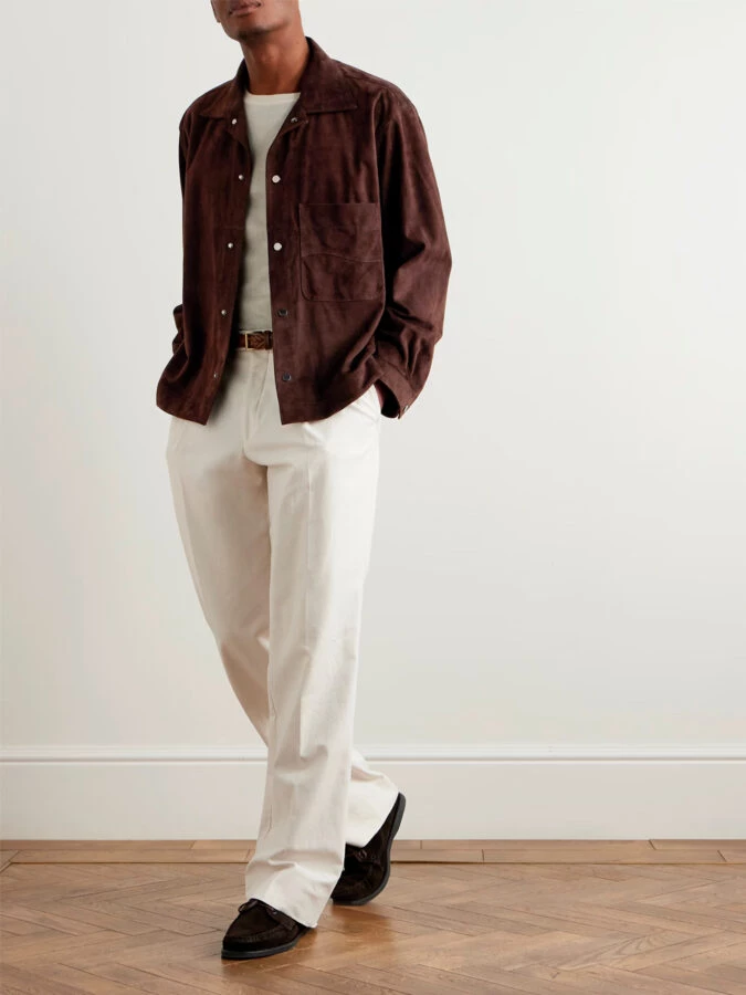 Look con chaqueta de ante marrón chocolate, pantalón blanco de pinzas, cinturón trenzado y mocasines de ante