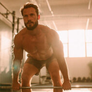 Hombre de 30 años atractivo levantando peso muerto en un gimnasio iluminado con luz natural