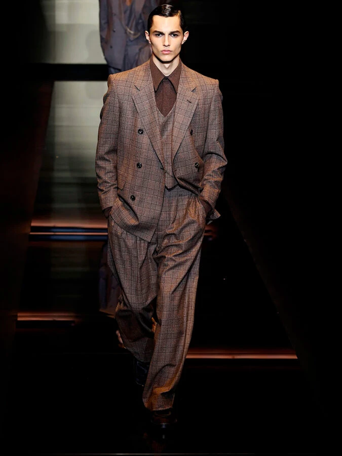 Modelo con traje marrón de tres piezas con cuadros de Emporio Armani otoño-invierno 2025.