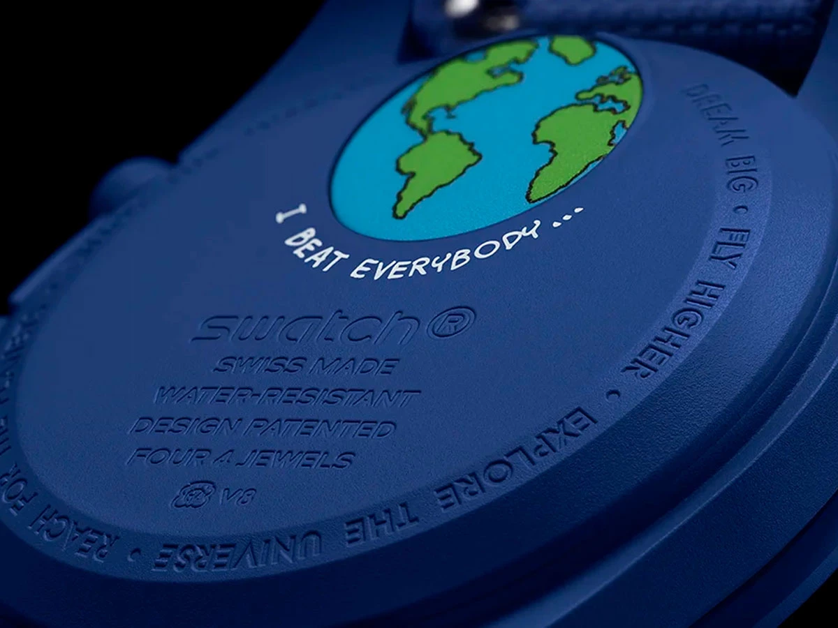 Tapa trasera del reloj MoonSwatch con la frase “I beat everybody” bajo la imagen del planeta Tierra.
