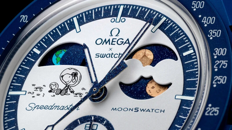 Detalle de la esfera del MoonSwatch EarthPhase Moonshine Gold con Snoopy, fases lunares y terrestres.
