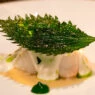 Plato del menú Celebration del restaurante Caelis con lubina y hoja de shiso crujiente.