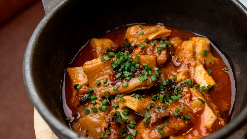 Guiso de callos, pata y morro servido en cazuela en el restaurante La Tasquería de Madrid.