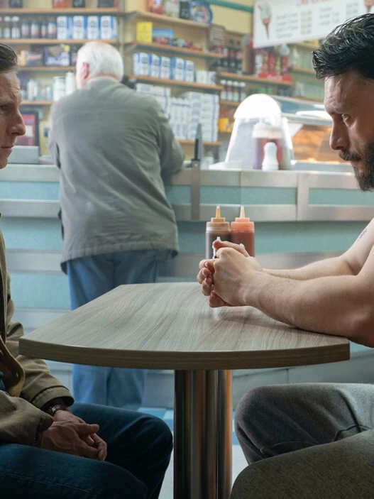 Protagonistas de la serie Half Man en una secuencia de la serie en la que aparecen sentados uno frente al otro en una cafetería