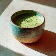 taza de té matcha en una superficie de piedra iluminada por luz natural