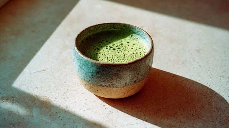 taza de té matcha en una superficie de piedra iluminada por luz natural