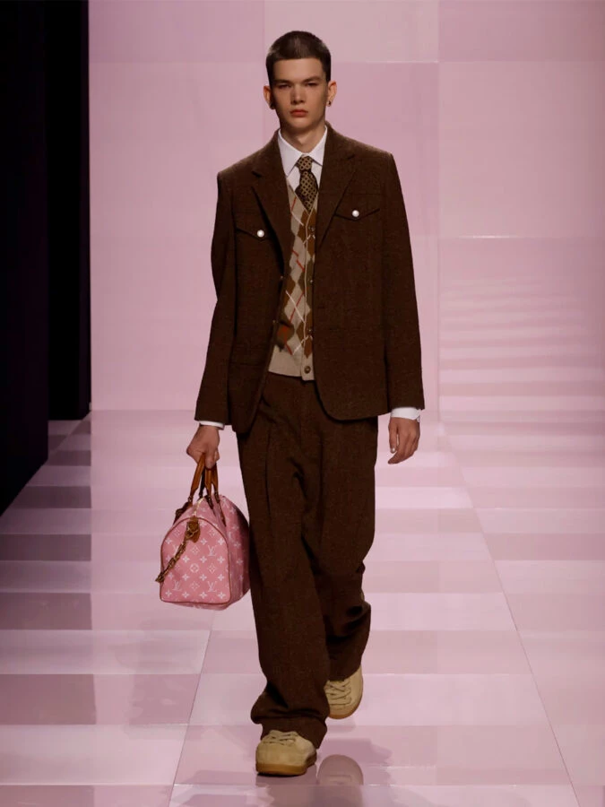 Modelo con jersey de rombos bajo americana gris de Louis Vuitton en la pasarela otoño-invierno 2025/2026