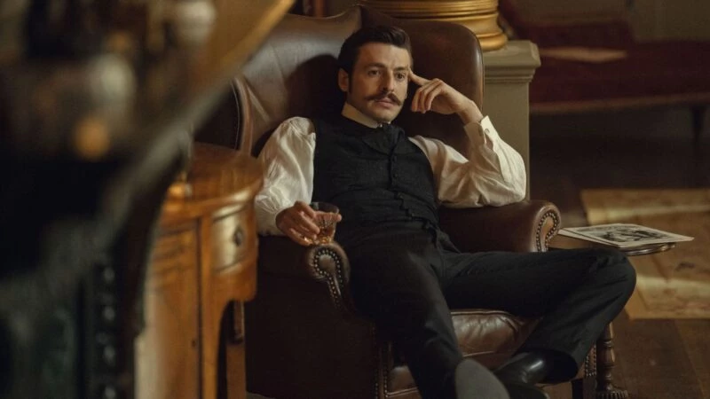 Escena de la serie La casa Guinness de Netflix en la que aparece el protagonista sentado en un sillón
