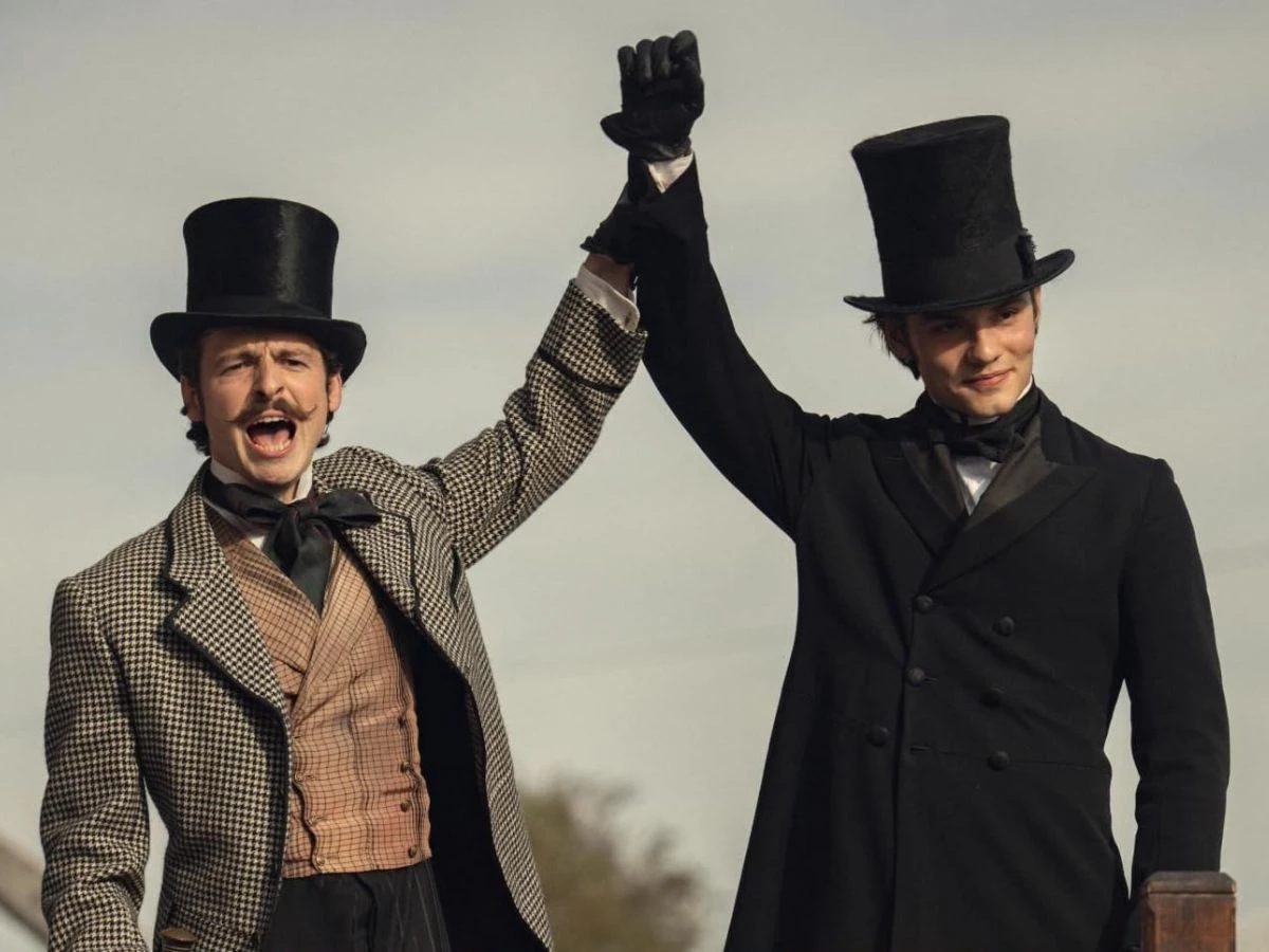 Escena de la serie La casa Guinness de Netflix en la que aparecen dos caballeros alzando la mano