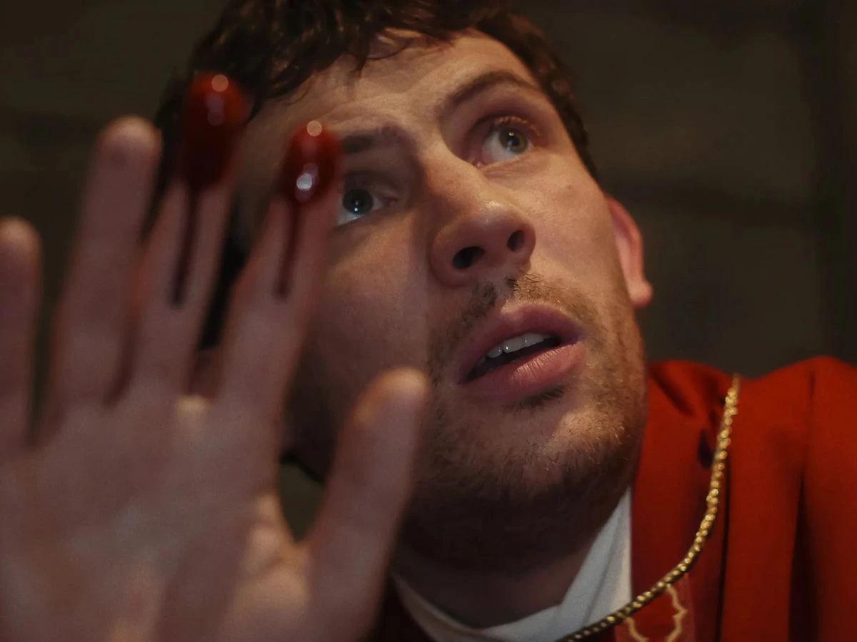 Josh O´Connor vestido de sacerdote en una Secuencia de la película Puñales por la espalda: de entre los muertos