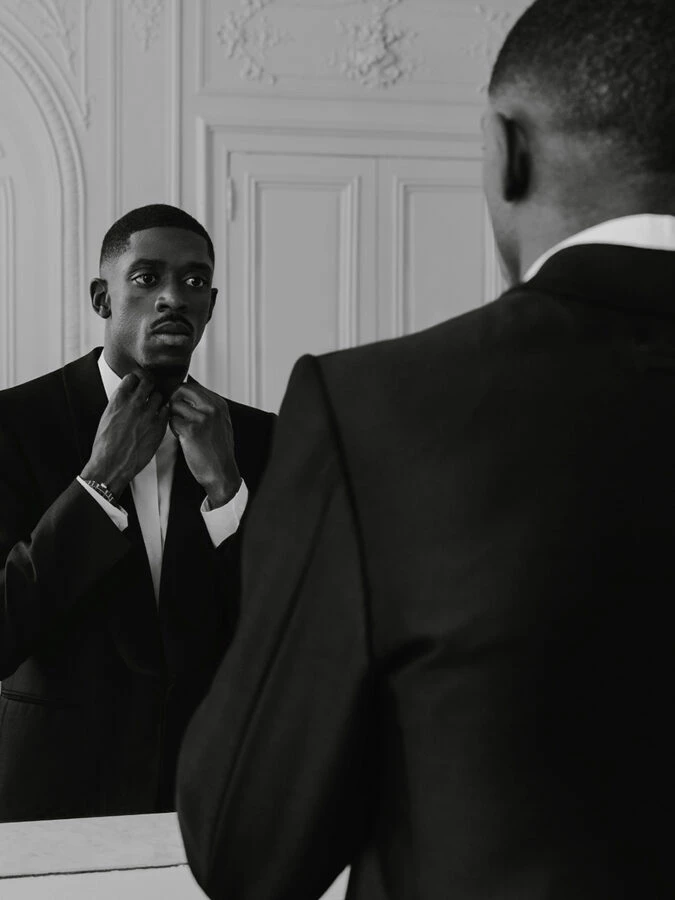El futbolista Ousmane Dembélé se ajusta la pajarita de su esmoquin frente al espejo de la suite de su hotel antes de la gala del Balón de oro 2025