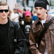 Las chaquetas que más molan para este otoño 2025 (y cómo tienes que combinarlas) dos chicos jóvenes, de veinte a treinta años, andando por la calle y vestidos con chaquetas actuales