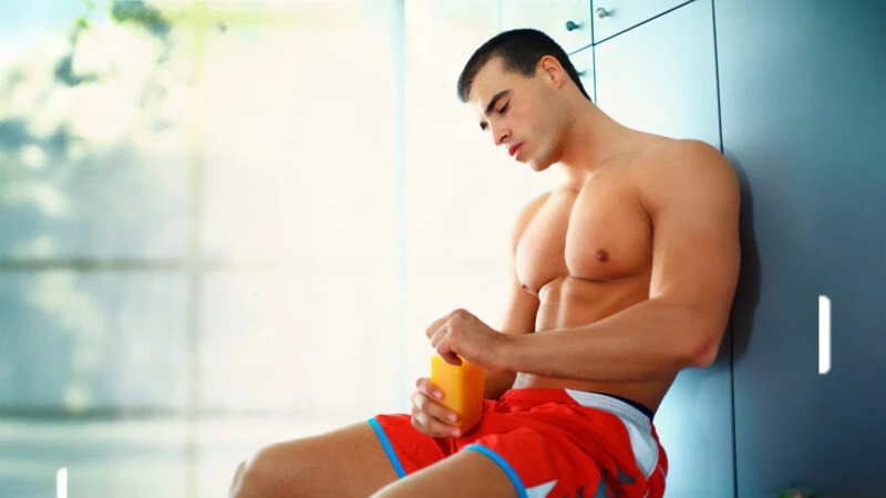 Joven tomando un suplemento deportivo tras entrenar en un vestuario