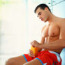 Joven tomando un suplemento deportivo tras entrenar en un vestuario