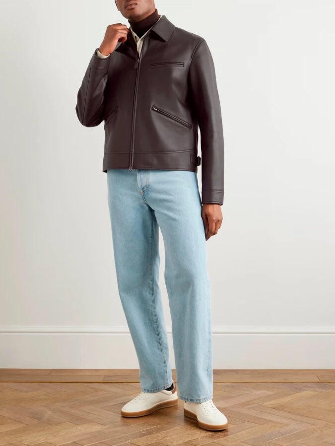 hombre vestido con chaqueta de cuero, jersey de cuello alto y pantalones vaqueros azul claro