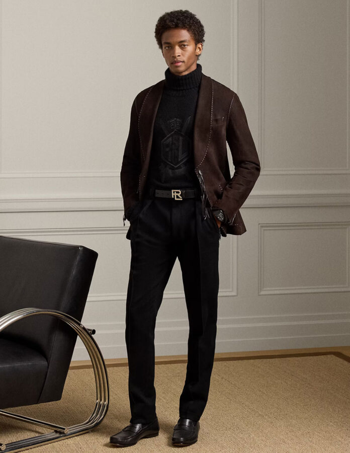 cómo combinar en pantalón negro de hombre: modelo vestido con un jersey de cuello alto negro y chaqueta de ante marrón.