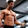hombre en un gimnasio entrenando biceps con mancuernas